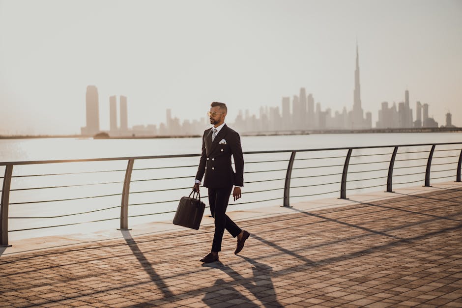 Digital Marketing Course for Washing Centre Owners: Grow Your Laundry Business Online Professional man in formal suit walking by Dubai waterfront with city skyline and Burj Khalifa in view.